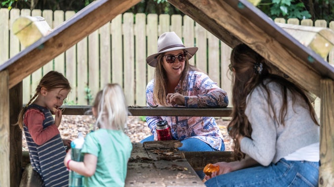 Family enjoying spending time together in the play area, Rook Wood, at Penrhyn Castle